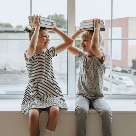 Twee kinderen houden stapel boeken op hun hoofd